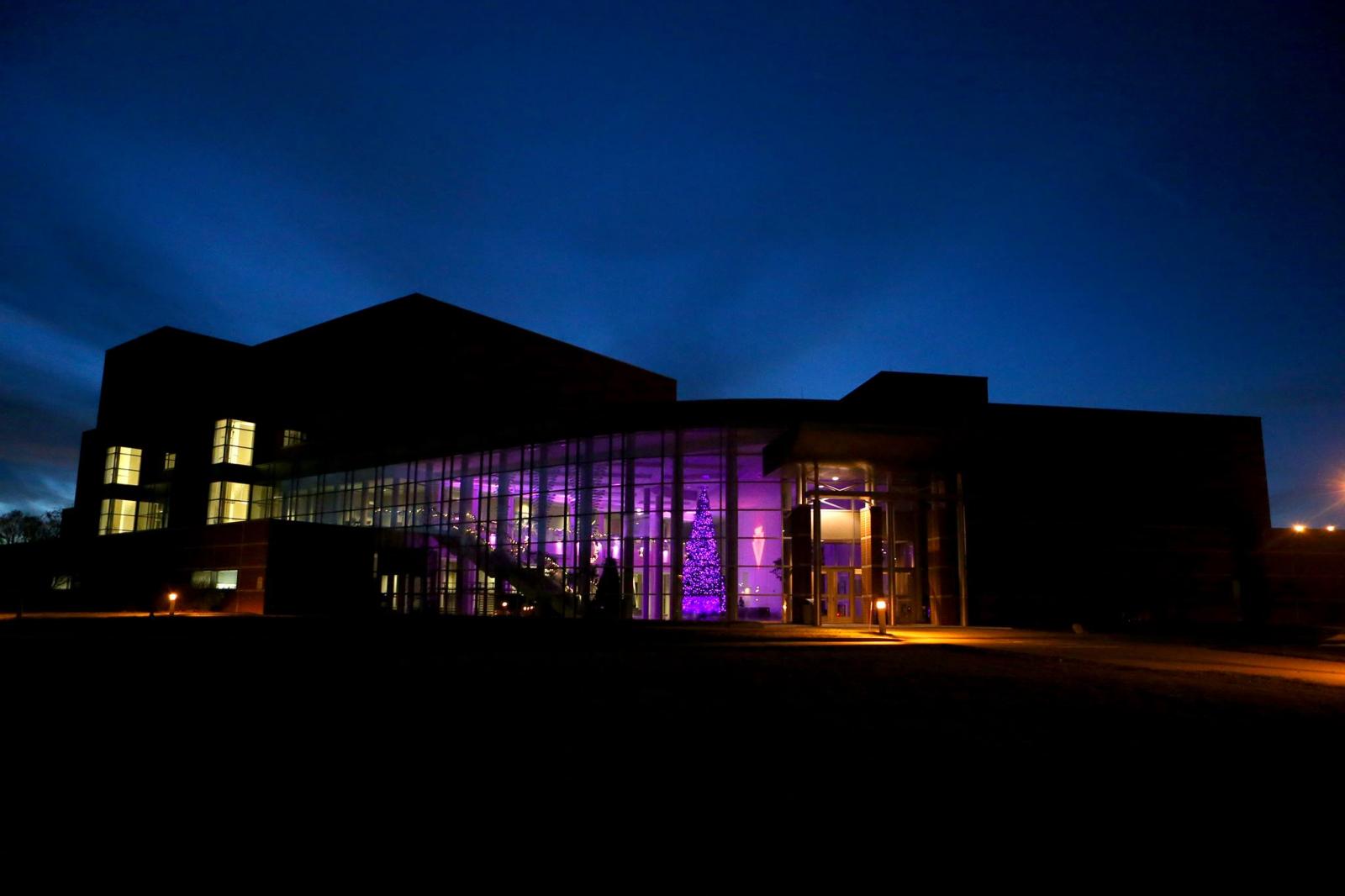 Outside the Gallagher Bluedorn at night. There are purple lights and christmas decorations lighting up the inside