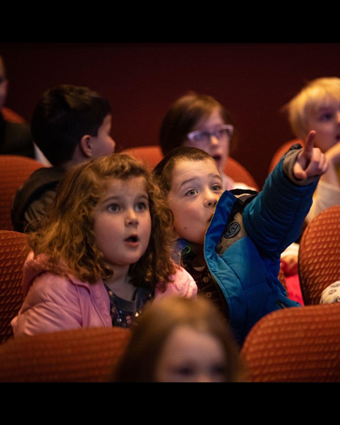 Two children pointing toward stage