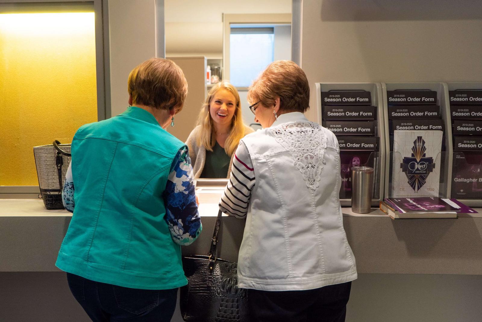 Two people purchase tickets at the Box Office with the ticket seller smiling
