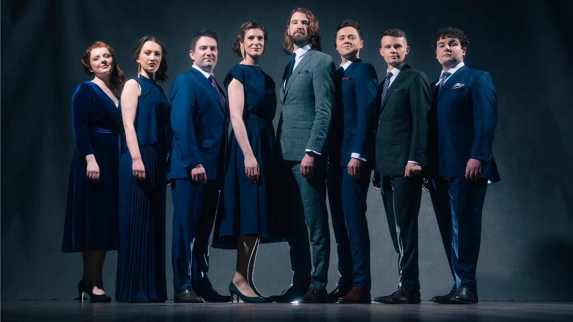 A group of people in suits and dresses posing for a portrait