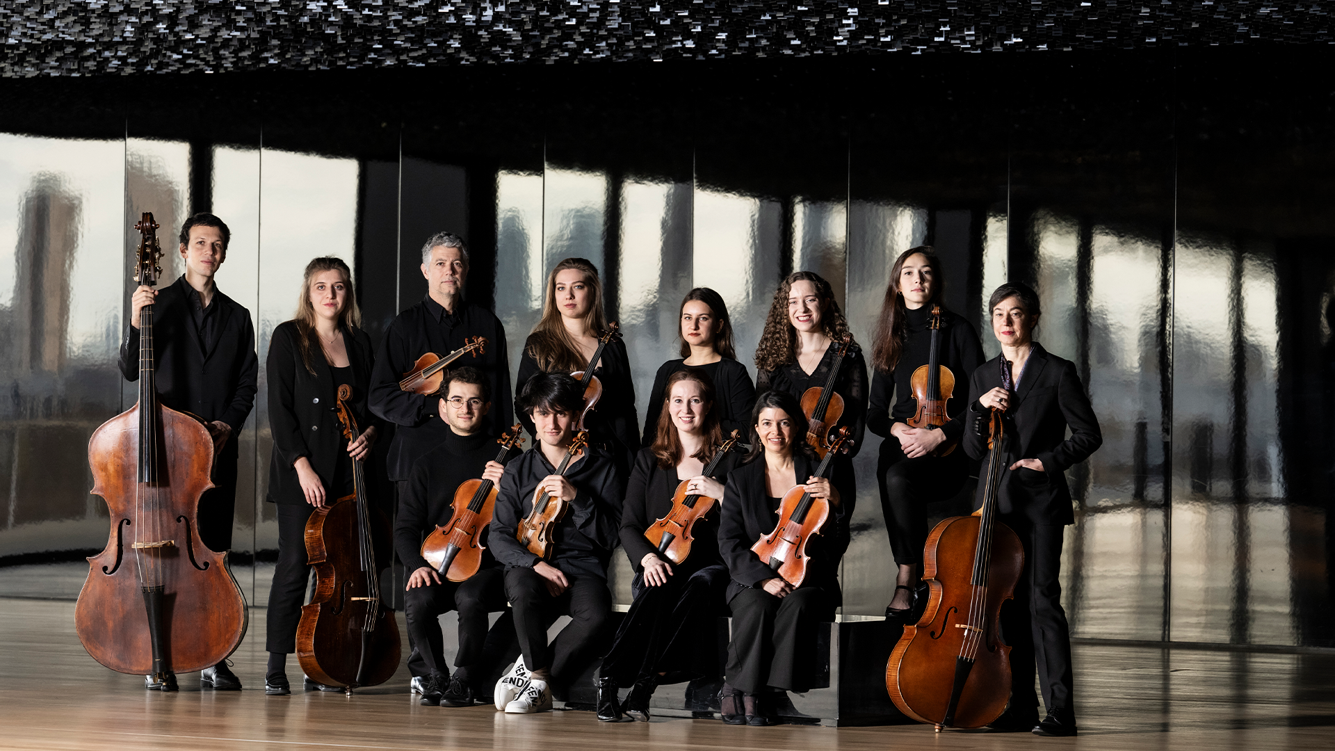 A group standing with instruments for a picture with windows in the background