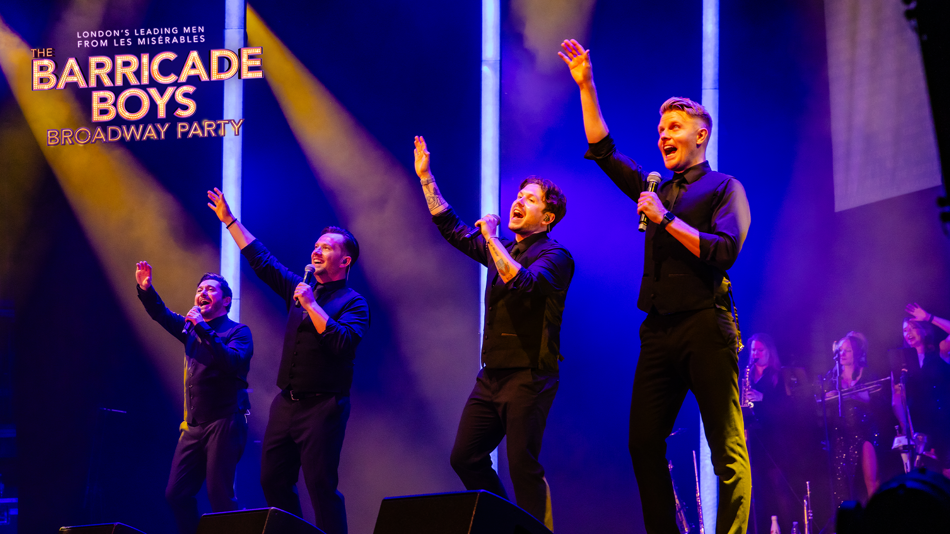 A group of men singing on a stage with purple lighting 