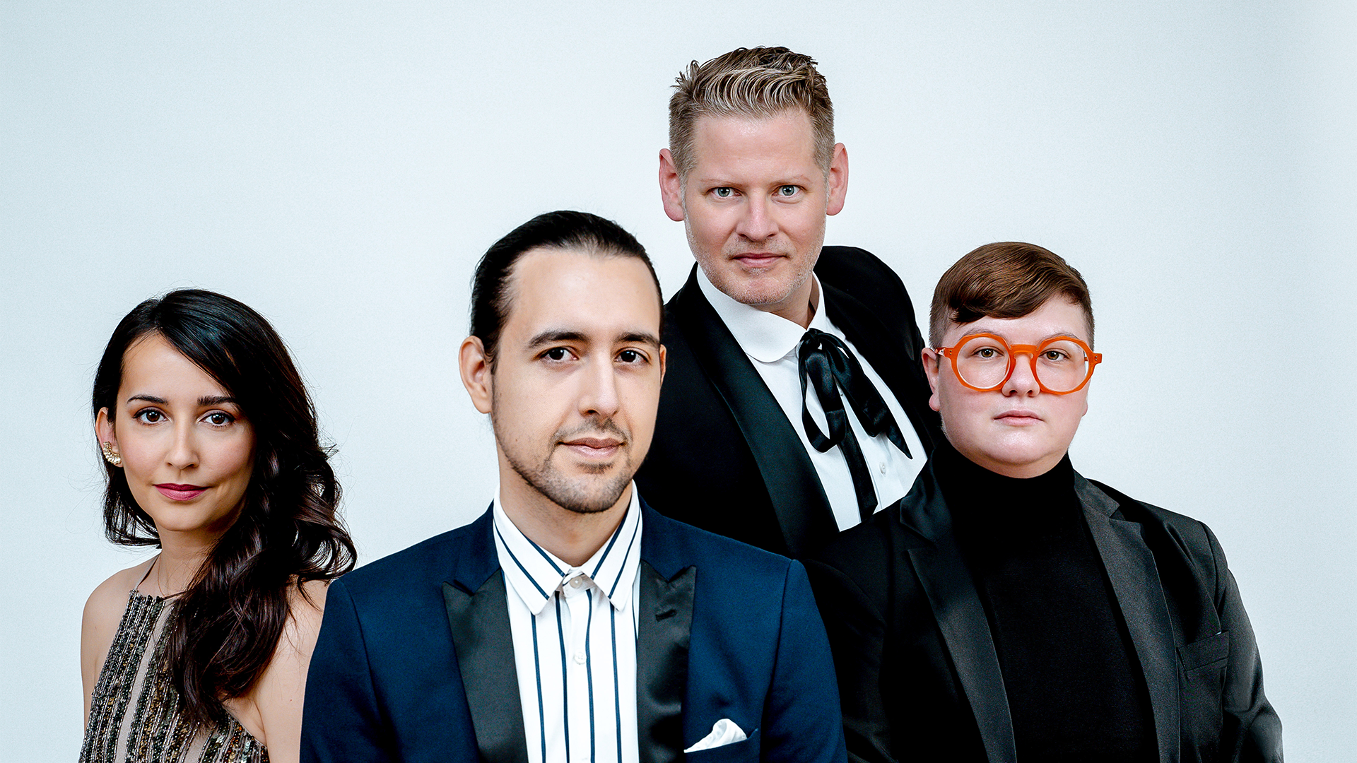 A group of people dressed up looking into the camera with a white background