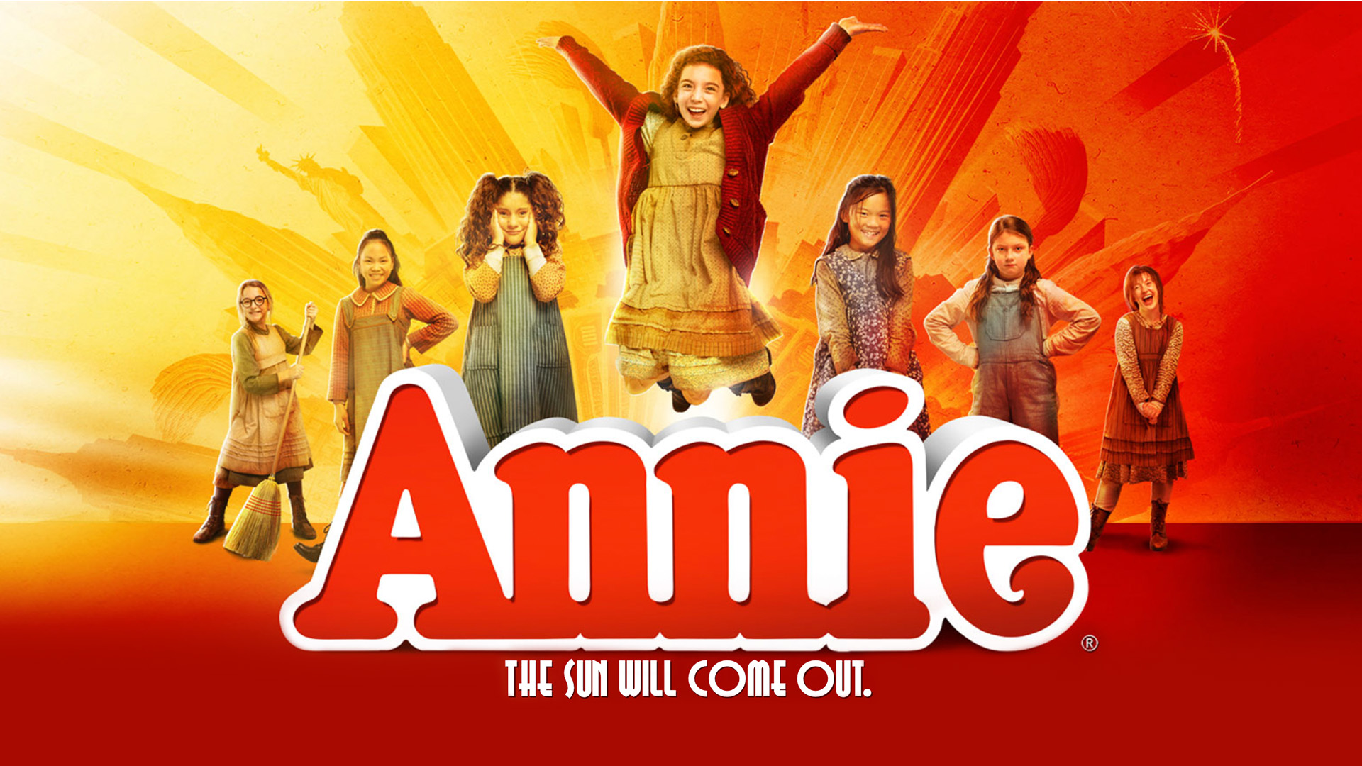 7 girls jumping above the word "annie" on a red, orange, and yellow background 