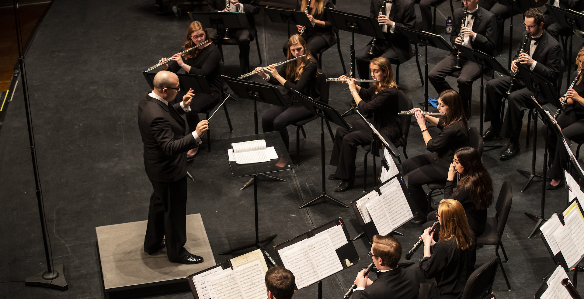 Members of the Symphonic Band playing their instruments in front of director