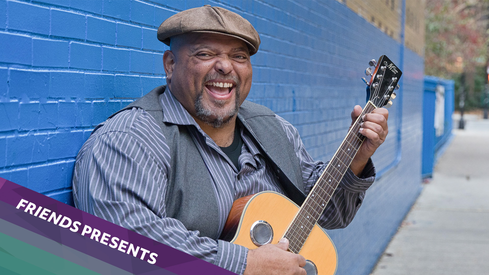 black man smiling sitting with guitar 