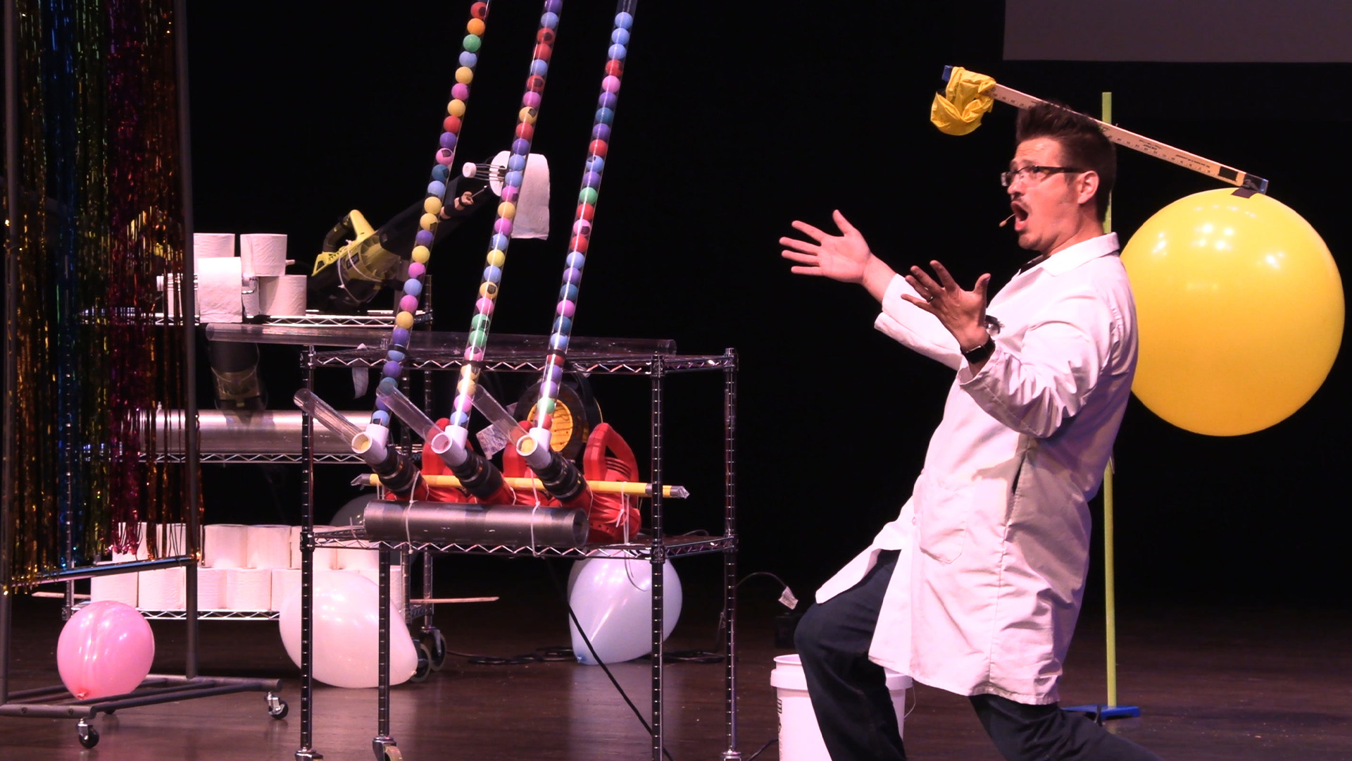 A man in science lab coat with his experiments in the background 