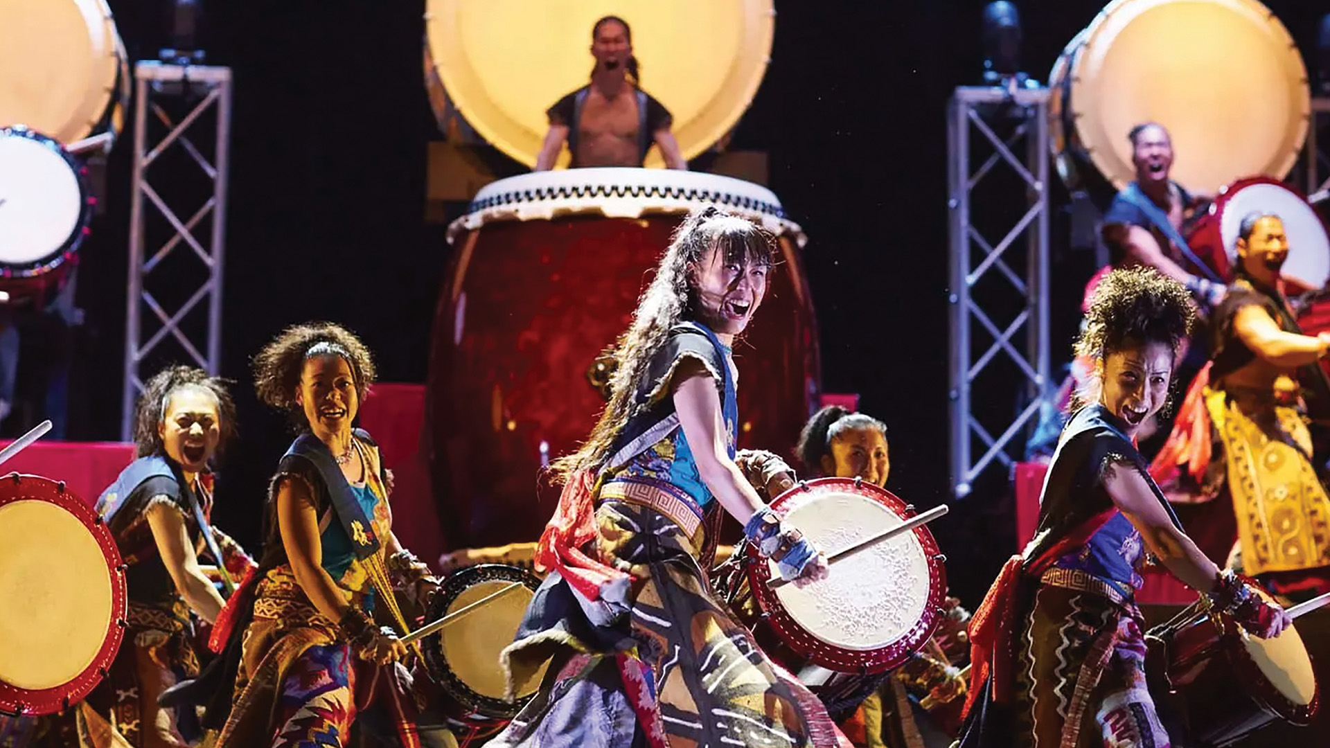 A group beating drums looking into the distance