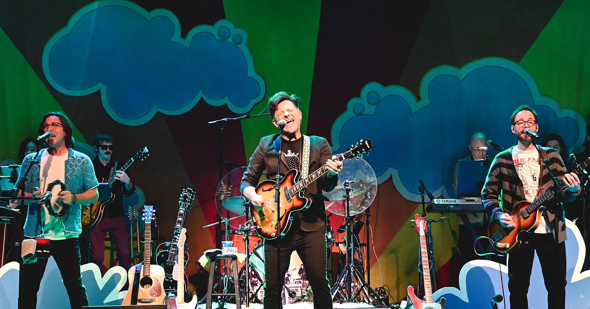 A beatles band playing with colorful cloud set in the background 