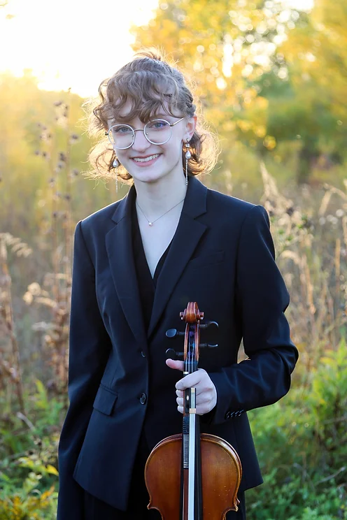 Laura Geerlings holding violin in field