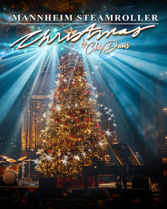 A christmas tree with colorful lights shining in the background in auditorium with rock instruments set up