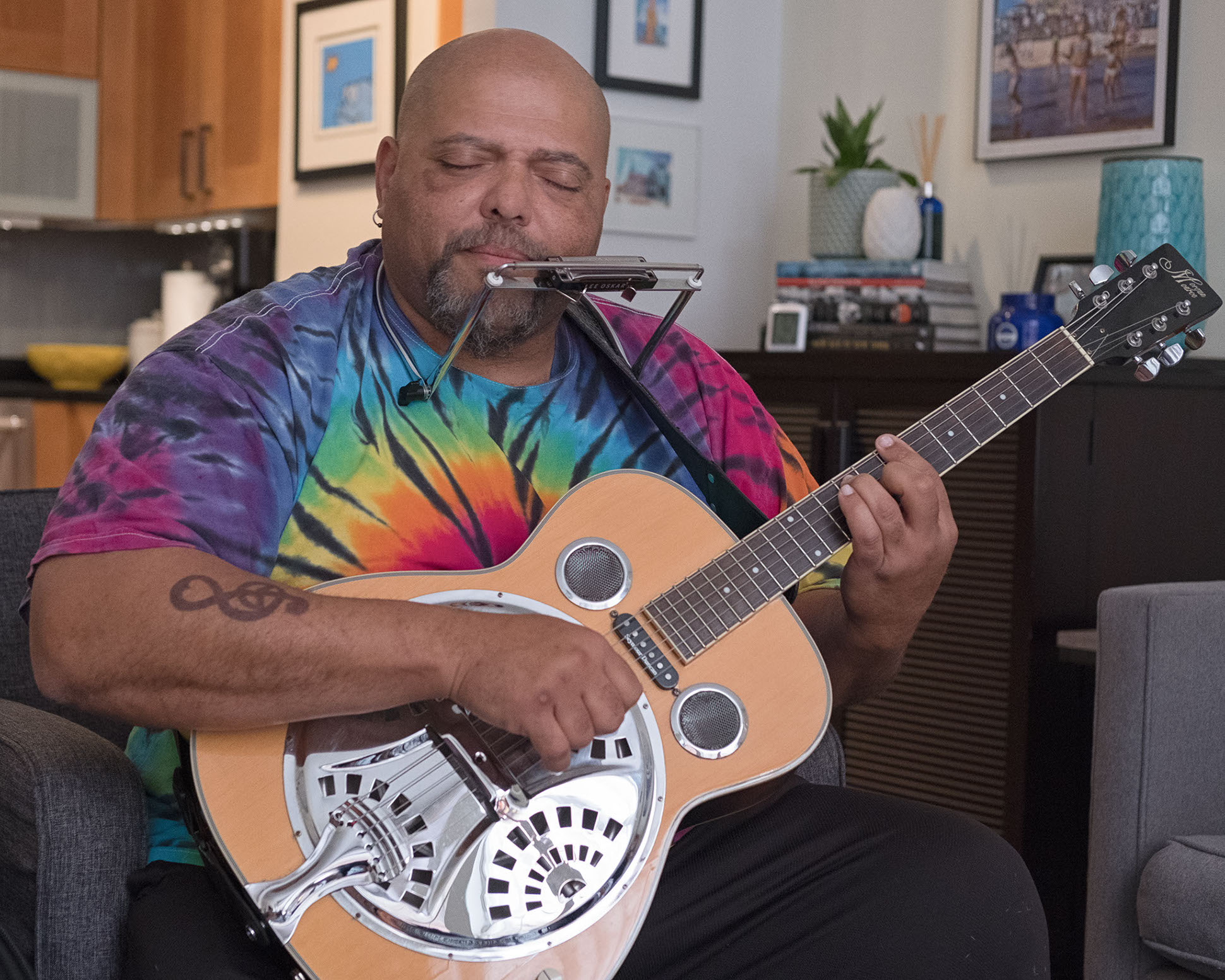 Kevin Burt in tie dye shirt playing guitar singing into microphone