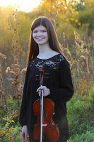 Emma Becker holding violin in field
