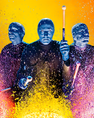 Blue Man Group playing a drum with paint splatters