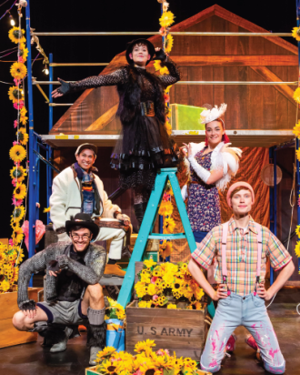 Actors dressed as barn animals pose in a barn scene.