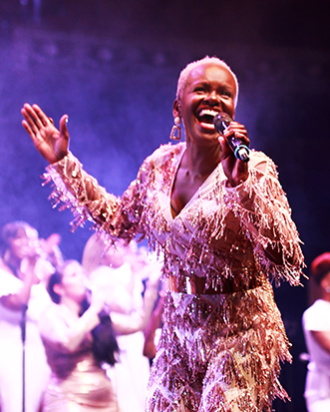 Member of the Kingdom Choir with microphone in her hand singing