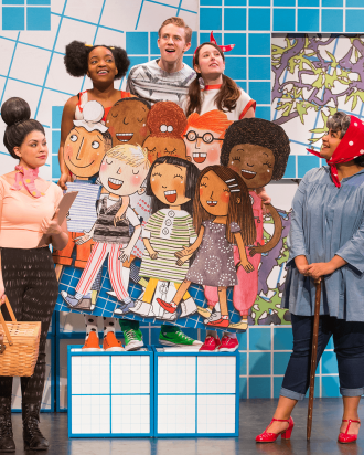 Actors playing school children on stage with cardboard cutouts of children's book illustrations.
