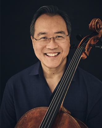 A man smiling holding a cello