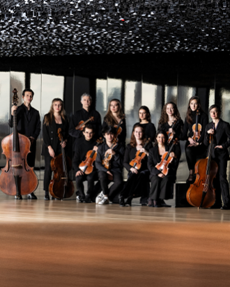 A group standing with instruments for a picture with windows in the background