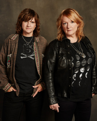 The Indigo Girls looking into the camera with a brown background