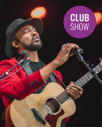 A man holding a microphone singing with guitar