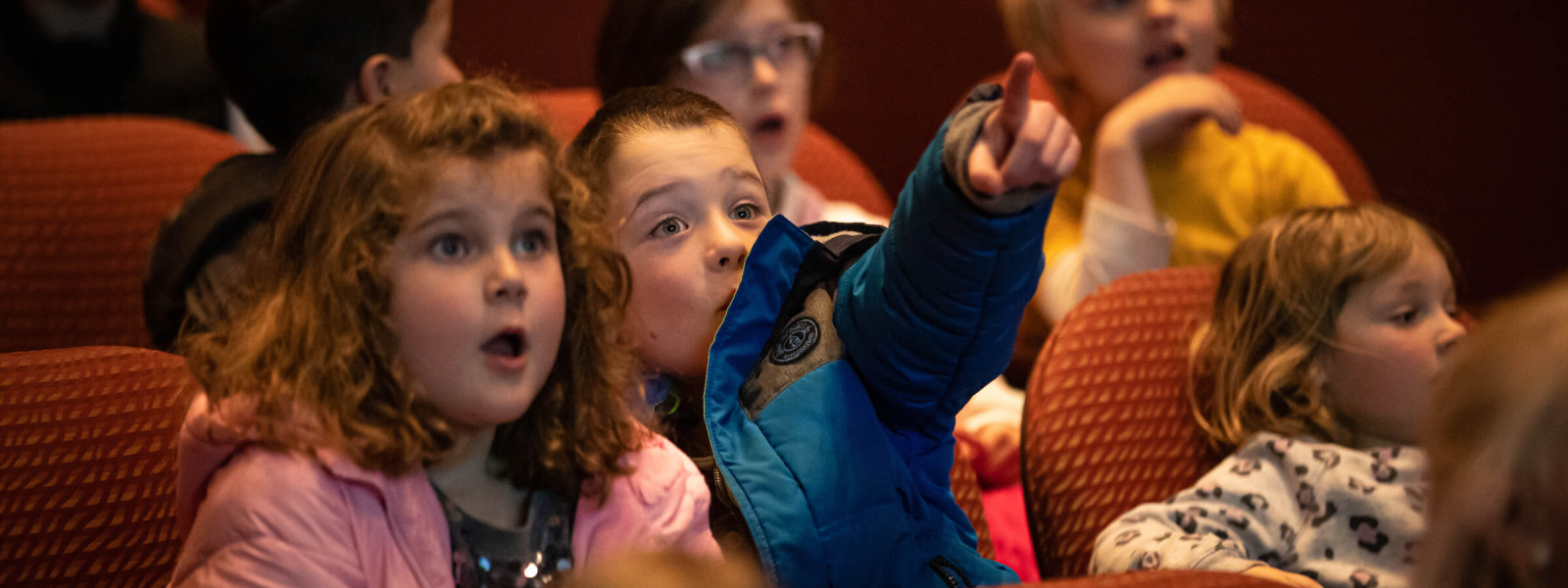 Two students with wide expressions on their faces point at the stage